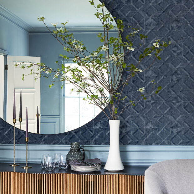 blue geometric wallpaper in a living space with a buffet unt and vase and mirror decorating