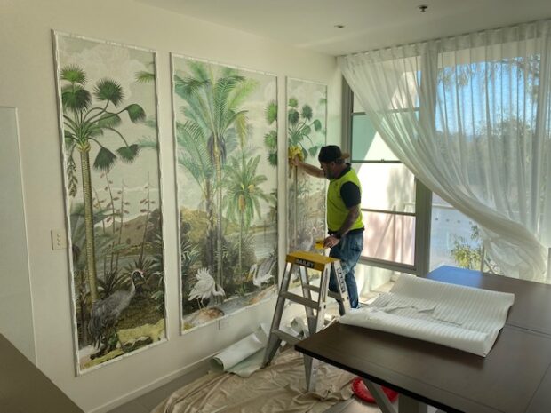 Lee installing wallpaper mural in panels