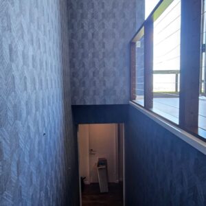Blue Arte textured wallpaper applied to stairs and room walls throughout